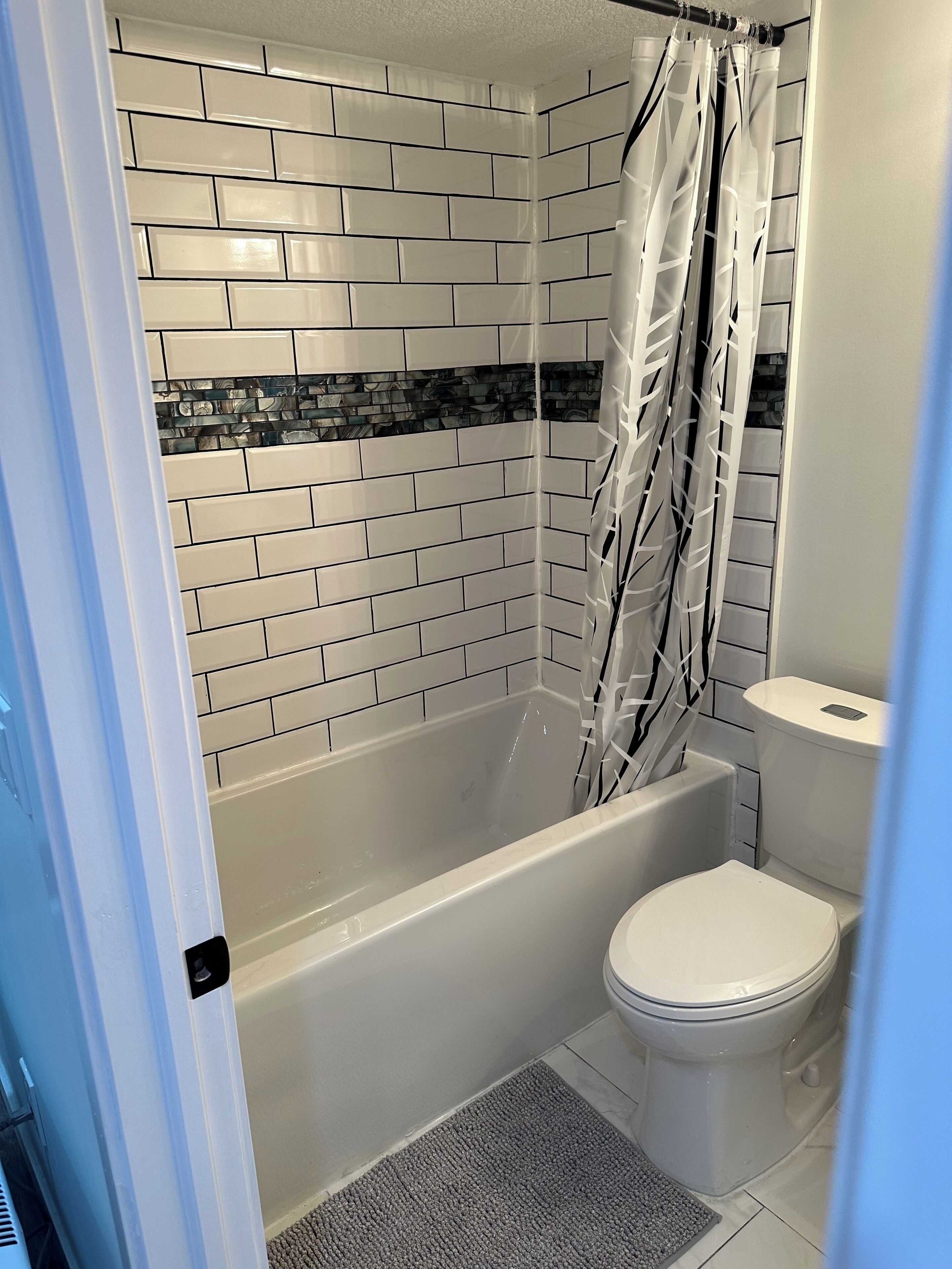 Une salle de bain avec une baignoire blanche, un rideau de douche et des toilettes.