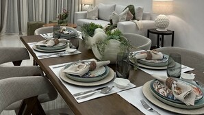 A modern dining area with a wooden table set for a meal, surrounded by comfortable seating. - Ámari, Spacious beach front 3-bedroom apartment with pool in sunny Puerto Plata (Puerto Plata)