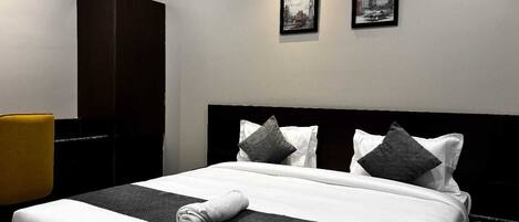 A hotel room with a large bed, a wardrobe, and two framed pictures on the wall.