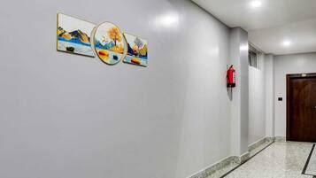 Un pasillo con tres cuadros enmarcados, un extintor y una puerta.