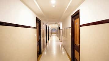 Un largo pasillo bien iluminado con puertas a ambos lados, que conduce a habitaciones individuales.