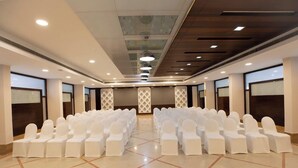 A conference room with rows of white chairs and a polished floor.