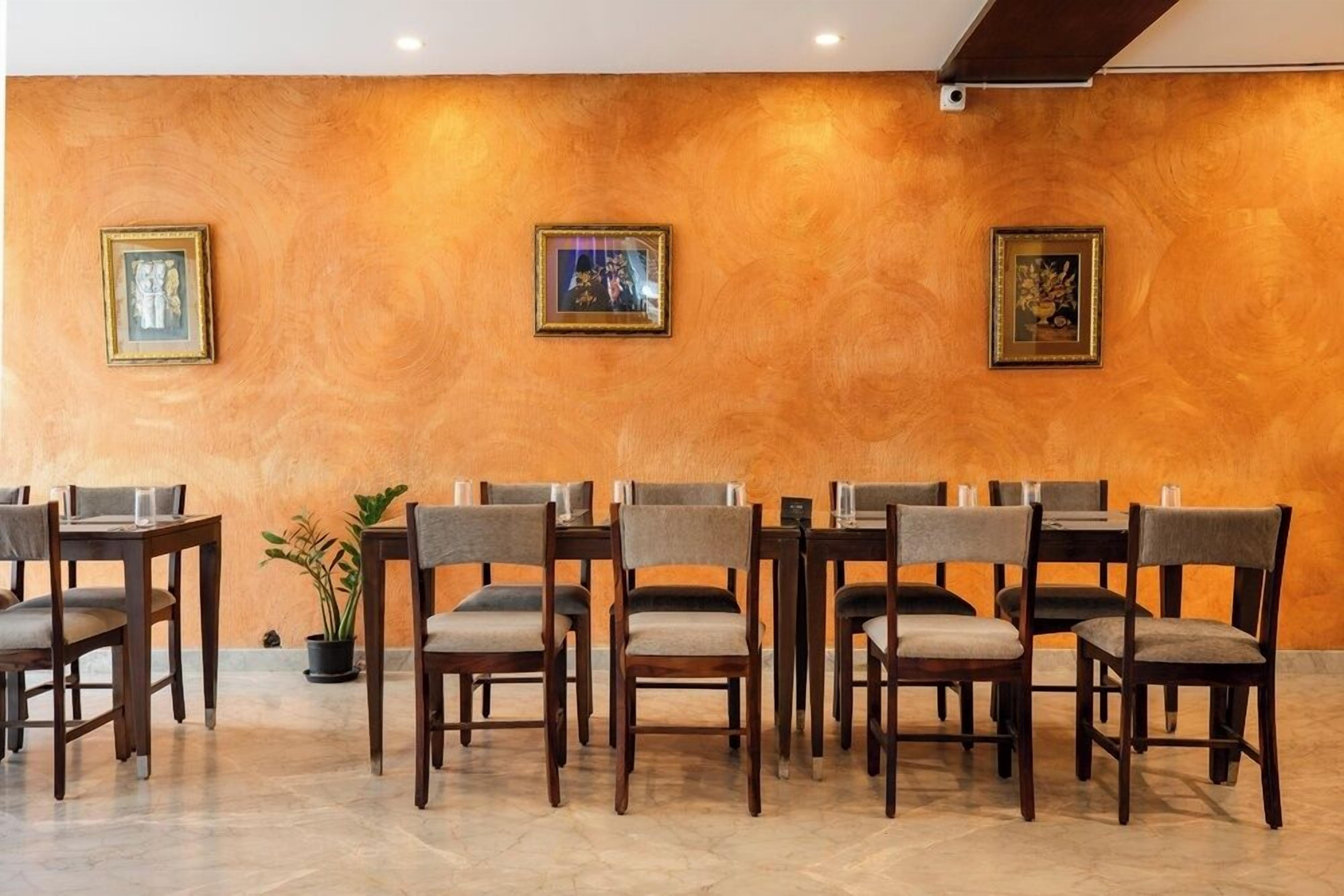 Un salón de conferencias con mesas y sillas de madera, cuadros en la pared y una planta en maceta.