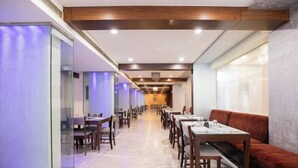 A hotel dining area with long tables, chairs, and a sofa.