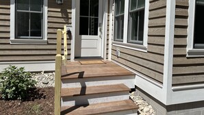 A house with a front porch, a wooden staircase, and a welcome mat. - Pine Cottage Big Glen Lake Private Access (Maple City)
