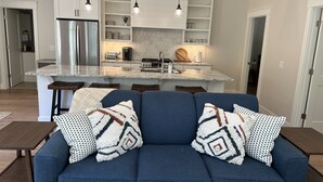 A modern kitchen with a central island, stainless steel appliances, and pendant lighting. - Pine Cottage Big Glen Lake Private Access (Maple City)