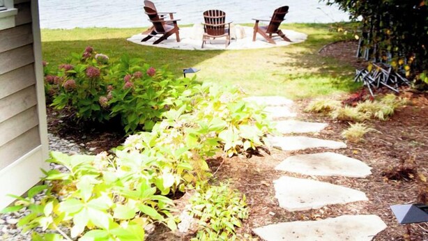 A pathway leading to a deck with Adirondack chairs overlooking a body of water. - Pine Cottage Big Glen Lake Private Access (Maple City)