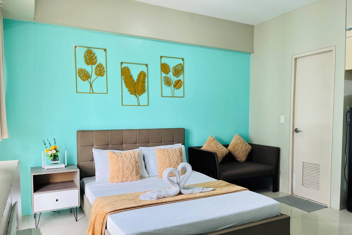 A hotel room with a bed, bedside tables, a desk, and a door.