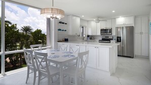 A modern kitchen with white cabinetry, stainless steel appliances, and a dining area with a table and chairs. - Island Beach Club 340B | Spacious and Upscale Beach Residence | Pet-Friendly (Sanibel)