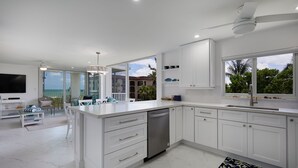 A modern kitchen with white cabinetry, a built-in dishwasher, and a large window offering a view of the outdoors. - Island Beach Club 340B | Spacious and Upscale Beach Residence | Pet-Friendly (Sanibel)