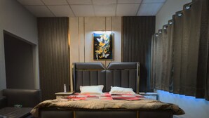 Un dormitorio moderno con una cama grande, una mesita de noche, una obra de arte en la pared y una ventana con cortinas.