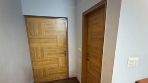 Un pasillo con suelo de madera y dos puertas de madera.