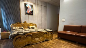 Un dormitorio con una cama grande, un sofá de cuero marrón, piso de madera e imagen colgada en la pared.