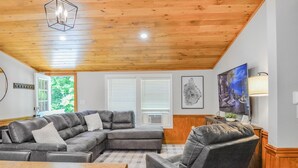 A living room with a sectional sofa, a coffee table, and a television. - Cranmore Ski Retreat • Arcade + Firepit + Dogs OK! (Conway)