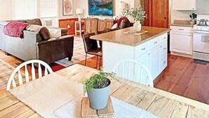 A cozy living room with a sofa, a dining table with chairs, a kitchen area with cabinets and appliances, and a wooden ceiling. - Cranmore Ski Retreat • Arcade + Firepit + Dogs OK! (Conway)