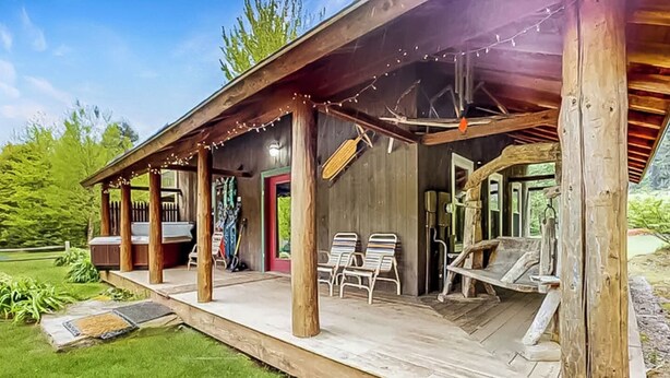 Un chalet rustique doté d’une terrasse en bois, de meubles d’extérieur et de guirlandes lumineuses.