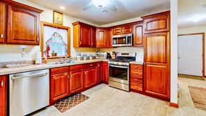 A kitchen with wooden cabinets, stainless steel appliances, and a ceiling fan.