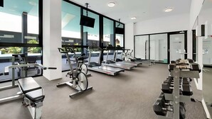 Une salle de sport moderne équipée de vélos d’appartement, de tapis de course et d’appareils de musculation.