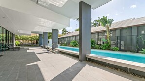 Un espace piscine extérieur moderne, offrant une vue dégagée sur la piscine, des chaises longues et un coin salon abrité.