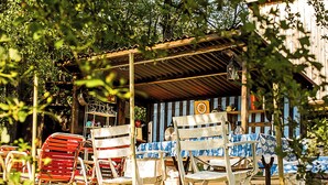 Un espace extérieur abrité, avec des chaises et une table, entouré d’arbres.