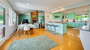 A modern kitchen with a central island, bar stools, and a dining area with a table and chairs. - Mtn-View Home w/ Pickleball Court in Louisville! (Louisville)