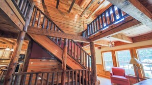 Un interior de madera con una escalera, una silla roja y una lámpara.