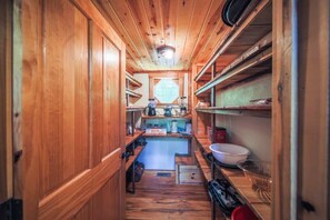A narrow, wooden-paneled kitchen with built-in shelves and a window.
