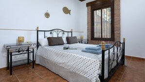 A bedroom with a bed, a nightstand, a window, and a wall clock.