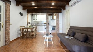 A cozy living area with a sofa, a dining table with chairs, and a kitchen in the background.