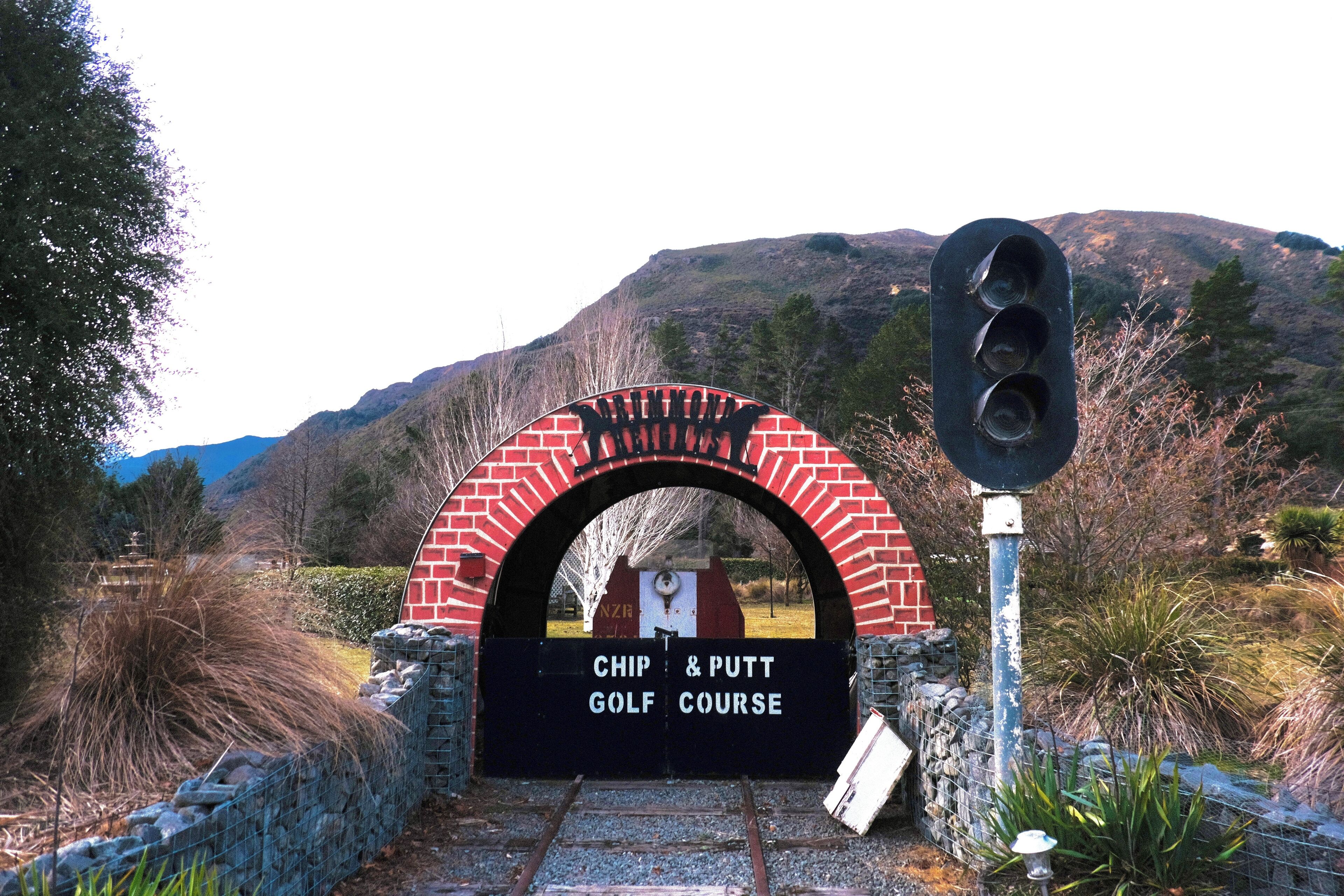 Ingresso a un campo da golf con un arco in mattoni e un semaforo.