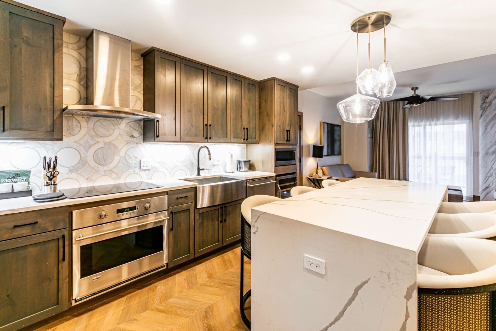 A modern kitchen with wooden cabinets, stainless steel appliances, and a marble countertop.