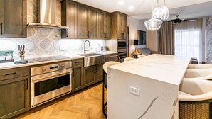 A modern kitchen with wooden cabinets, stainless steel appliances, and a marble countertop.