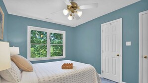 A bedroom with a bed, a window, a door, and a ceiling fan. - Sweetbay Retreat — Minutes from Fort Bragg, Methodist University, and Downtown! (Fayetteville)