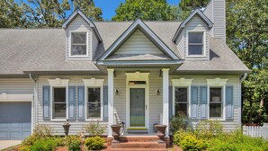A two-story house with a front porch, a garage, and a well-maintained garden. - Sweetbay Retreat — Minutes from Fort Bragg, Methodist University, and Downtown! (Fayetteville)
