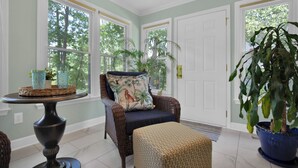 A room with a wicker chair, a small table with a basket, and a potted plant. - Sweetbay Retreat — Minutes from Fort Bragg, Methodist University, and Downtown! (Fayetteville)
