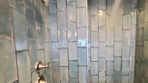 Un espace douche avec un mur carrelé, une pomme de douche et un robinet de réglage de la douche.