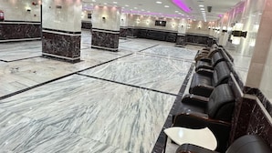 Un hall d’entrée spacieux doté d’un sol en marbre, de sièges en cuir noir et d’un éclairage d’ambiance violet.