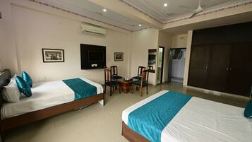 A hotel room with two single beds, a TV, a small table with chairs, and a wardrobe.