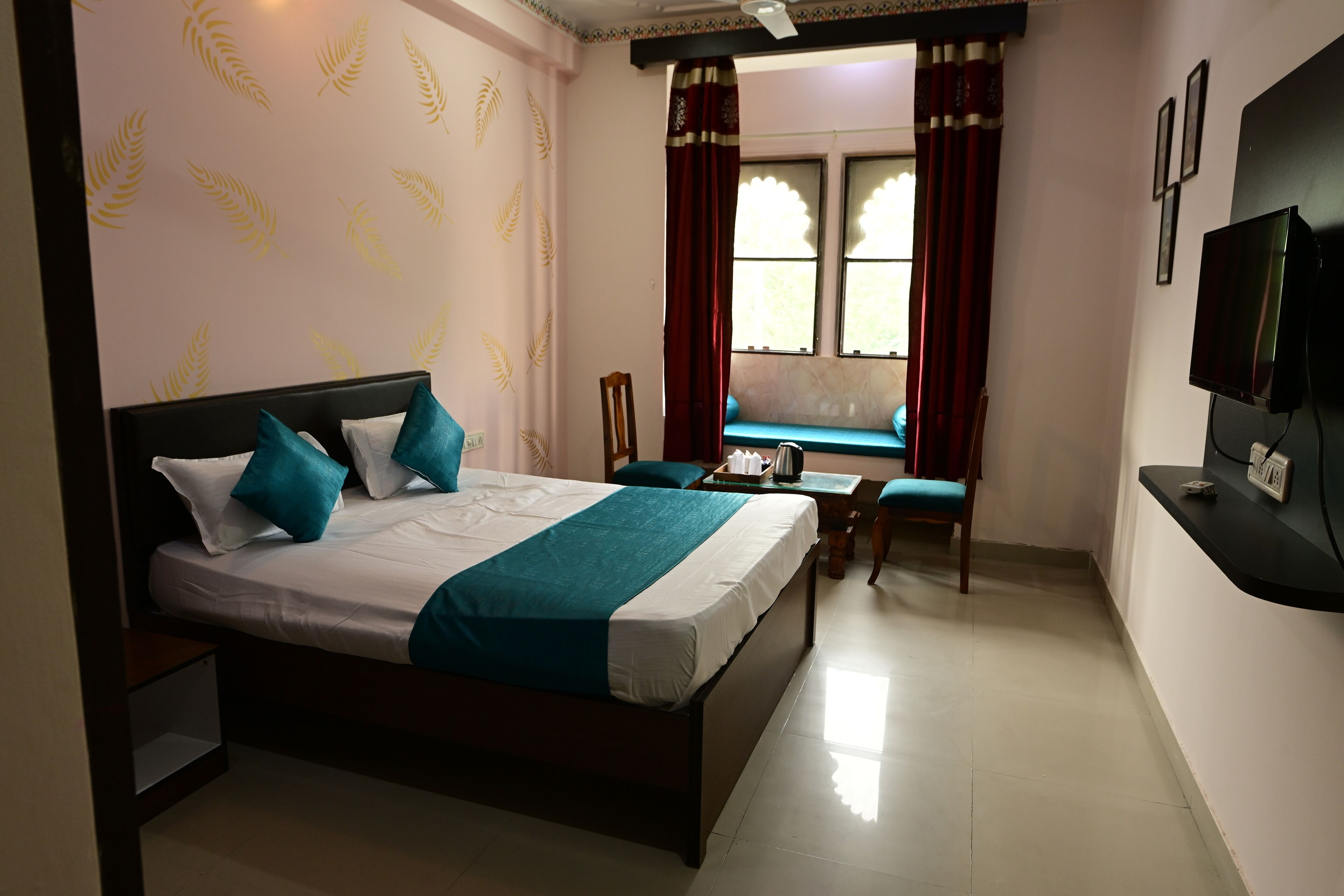 Habitación de hotel con cama, televisión, escritorio y ventana con cortinas.