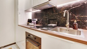Una cocina moderna con salpicadero de mármol, pileta de acero inoxidable y electrodomésticos integrados.