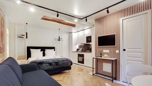 Una habitación de hotel moderna con cama, sofá, mesa de comedor y zona de cocina.