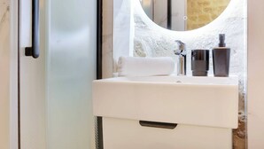 Un baño con un lavamanos blanco, un espejo y una toalla.