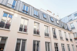 A multi-story building with balconies, large windows, and a flat roof with skylights.