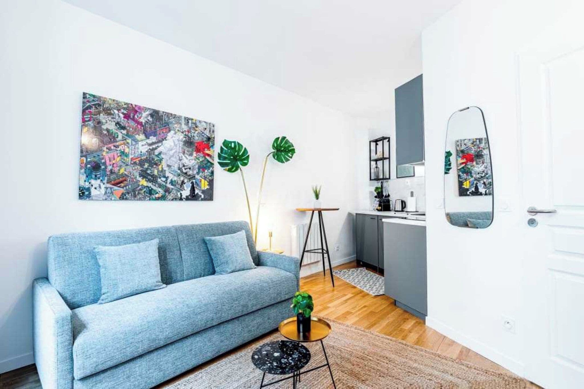 A modern living room with a grey sofa, a coffee table, a painting, and a mirror.