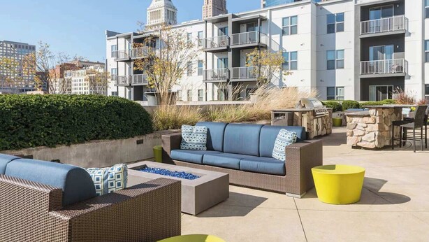 An outdoor patio area with seating, a fire pit, and a grill. - TWO CozySuites at the Banks 17 (Cincinnati)