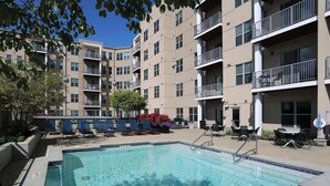 A swimming pool surrounded by lounge chairs and a building with balconies. - TWO CozySuites at the Banks 17 (Cincinnati)