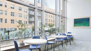 A modern office with large windows, blue chairs, and a white table. - TWO CozySuites at the Banks 17 (Cincinnati)