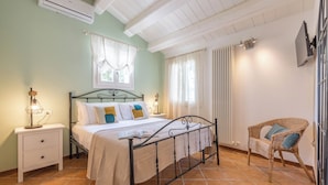 A bedroom with a bed, nightstand, chair, and a window with curtains. - La Finestra sul Mare - Apartment with a view (Gabicce Mare)