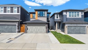 Une rangée de maisons modernes à deux étages, dotées de garages attenants, d’une pelouse bien entretenue et surplombées par un ciel bleu dégagé.