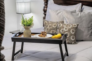 A bed with a tray holding a banana, a plate with pastries, and a potted plant. - Calgary Modern Suite • AC • Free Driveway Parking (Calgary)